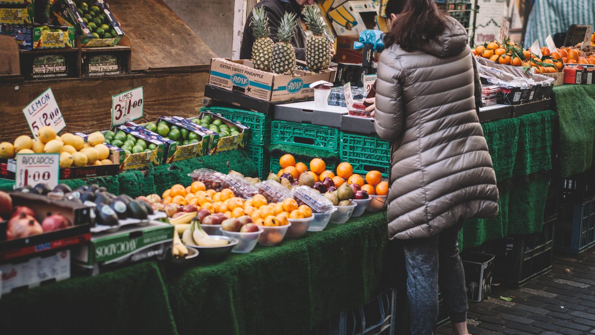 Person purchasing fruit from an outdoor market stand