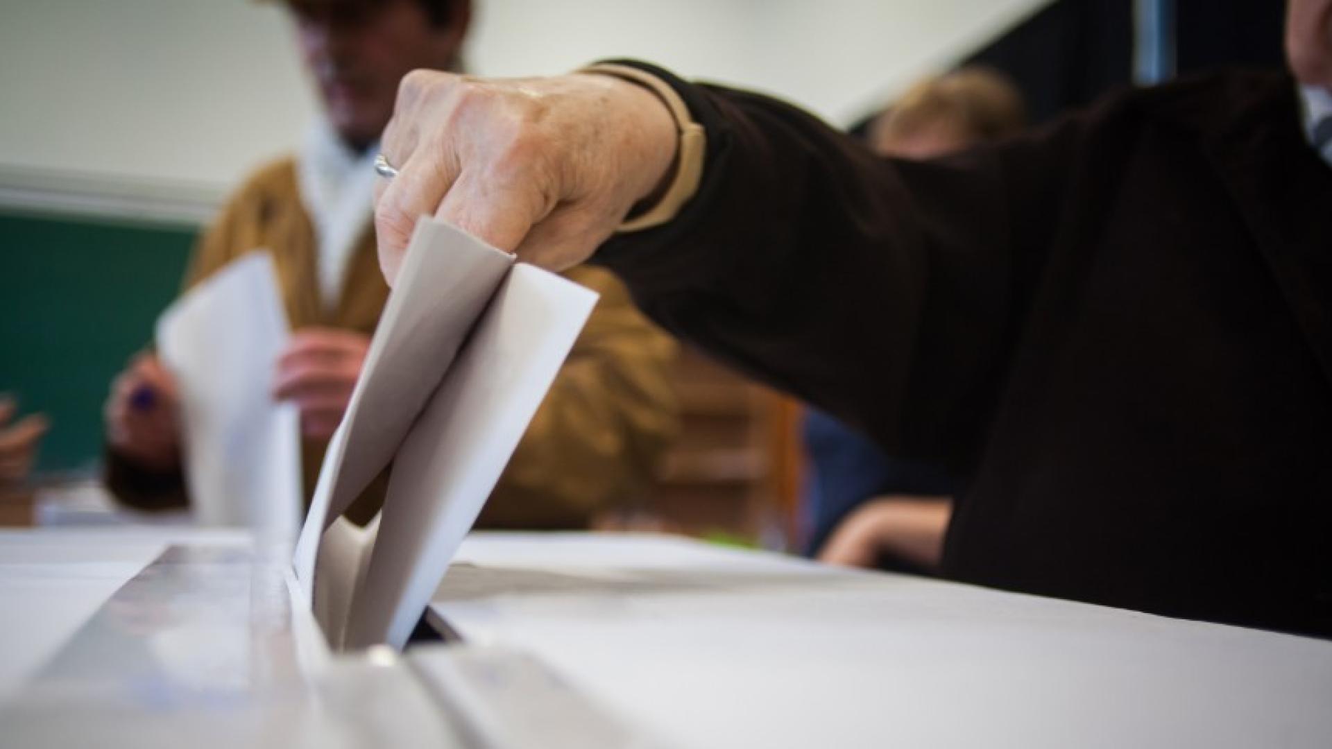 Person submitting an election vote within a box
