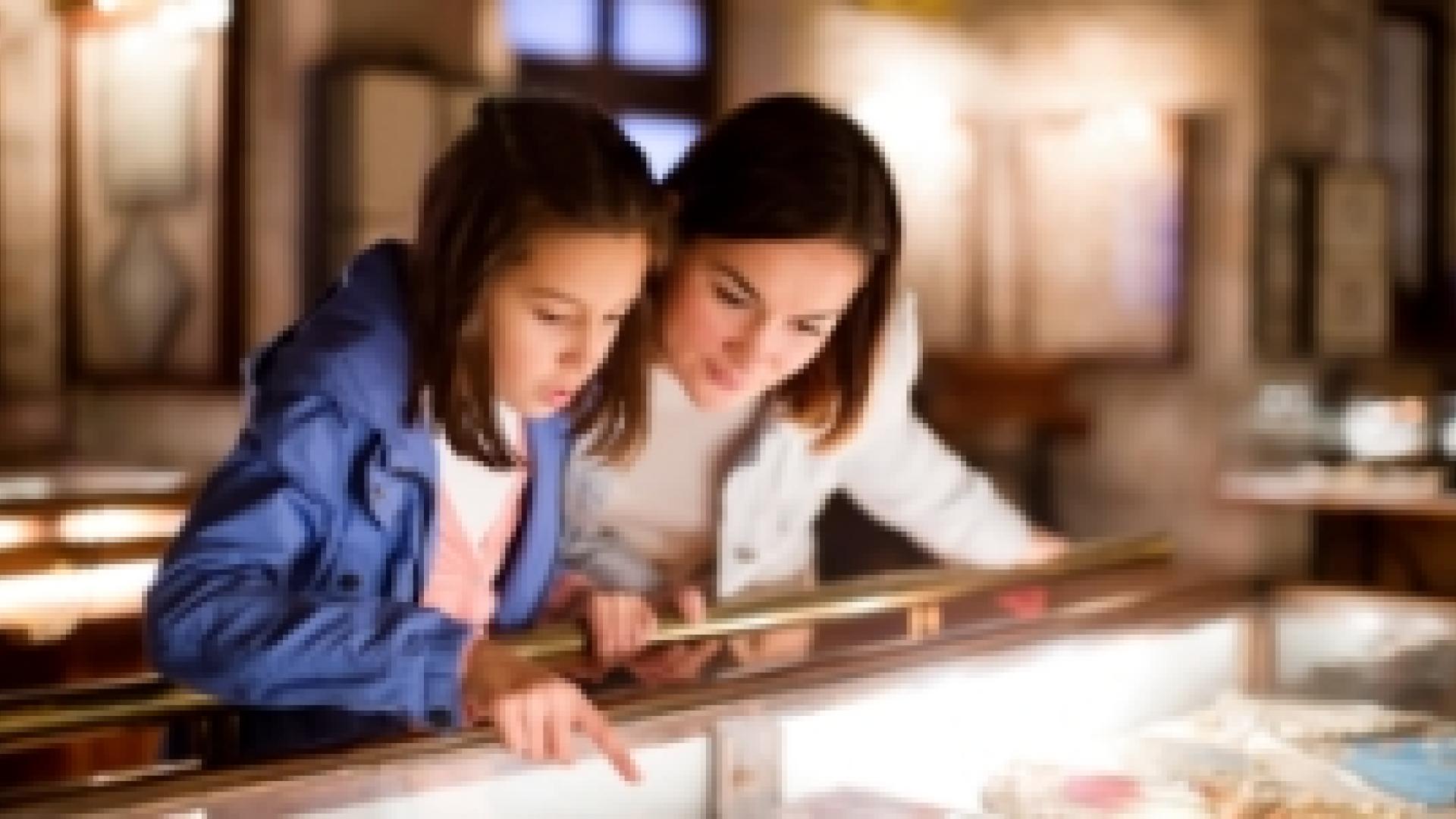 A mother and her daughter looking over a glass display pointing at an item
