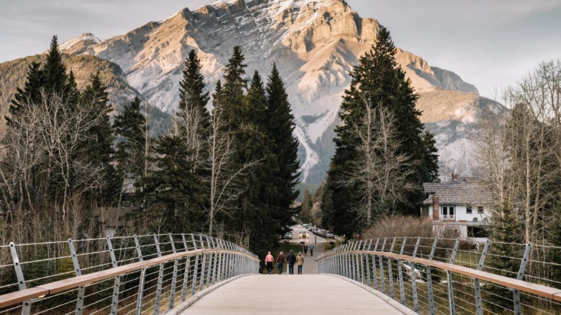 People walking on pathway bridge with mountains in the distance