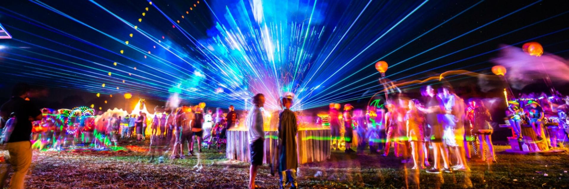 A blurred crowd of people with a large amount of neon lights across the screen