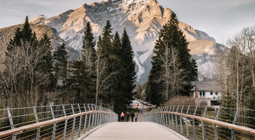 People walking on pathway bridge with mountains in the distance